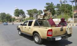 Taliban fighters sit on the back of a vehicle in the city
