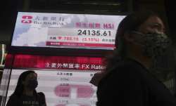People walk past a bank's electronic board showing the Hong