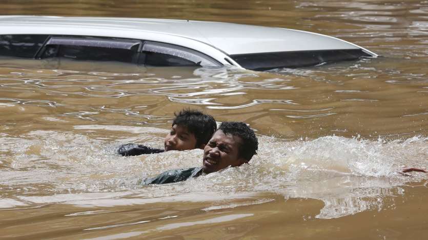 People swim through a flooded neighborhood following heavy rains in Jakarta, Indonesia.