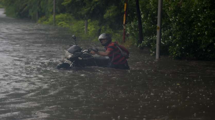 A commuter pushes his bike through a waterlogged street due to heavy rains, near ITO in New Delhi.